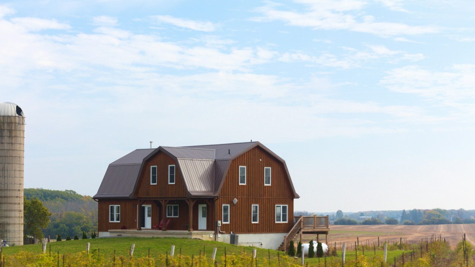 View of a red barn and silo on sprawling farmland, representing property division and unjust enrichment claims involving a family farm after separation and divorce in Ontario