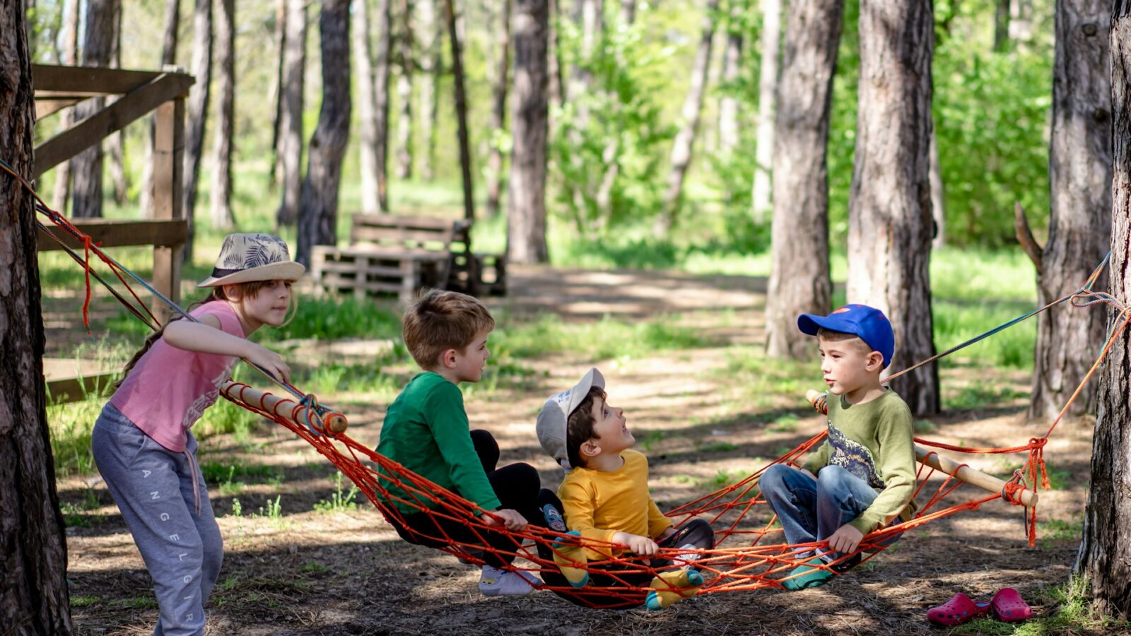 A group of kids playing on a hammock at a summer camp, representing parenting disputes in the summer regarding kids' camp schedules.