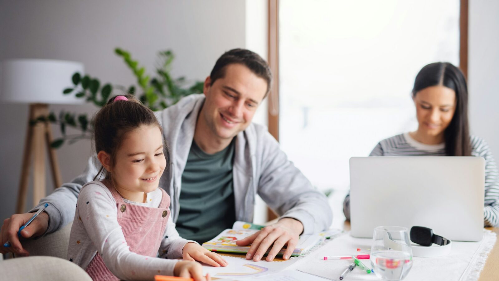 Two parents with a child at a table appearing to be doing homework, representing stepparents and child support.